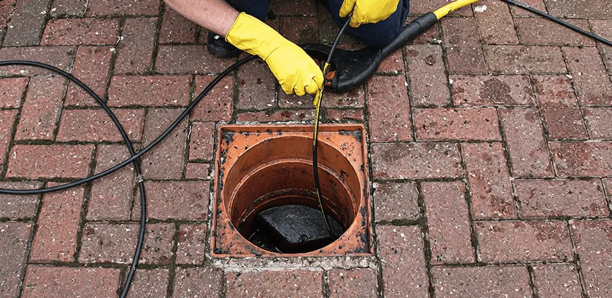 Drain cleaning technician using a drain snake to clear a clogged drain in Boston, MA