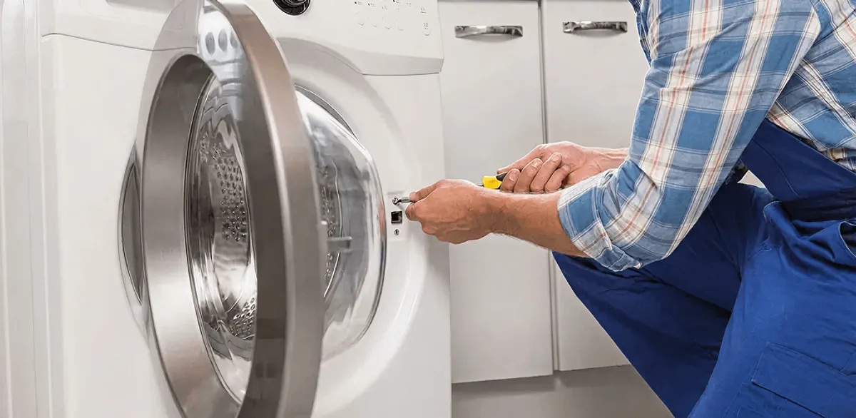 Handyman repairing a clothes dryer and checking electrical connections in Boston, MA