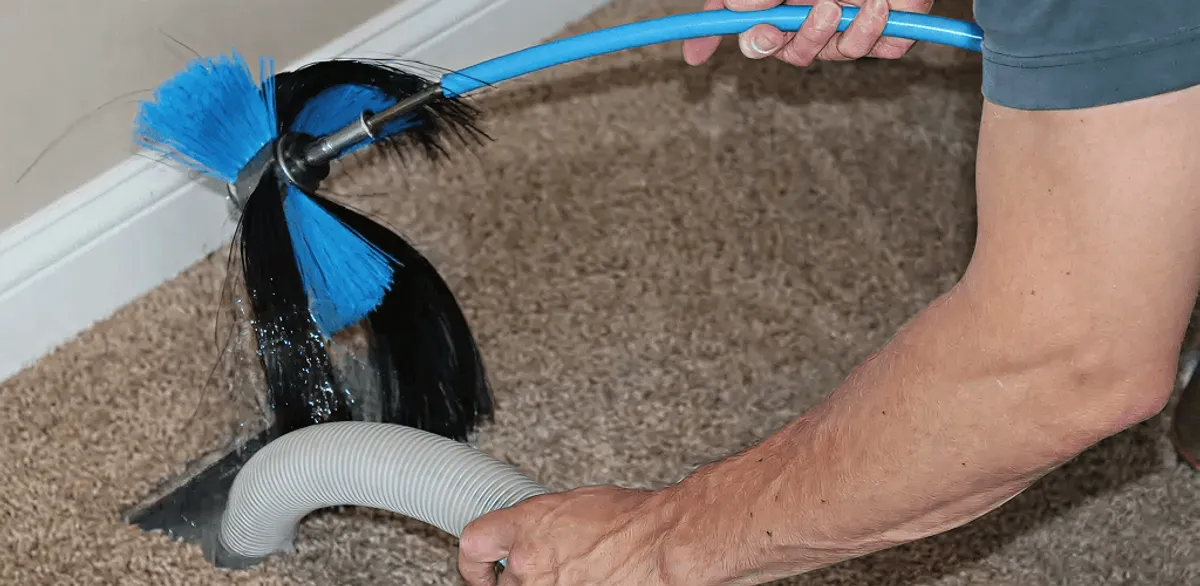 Dryer vent cleaning technician brushing lint from a vent line in Boston, MA