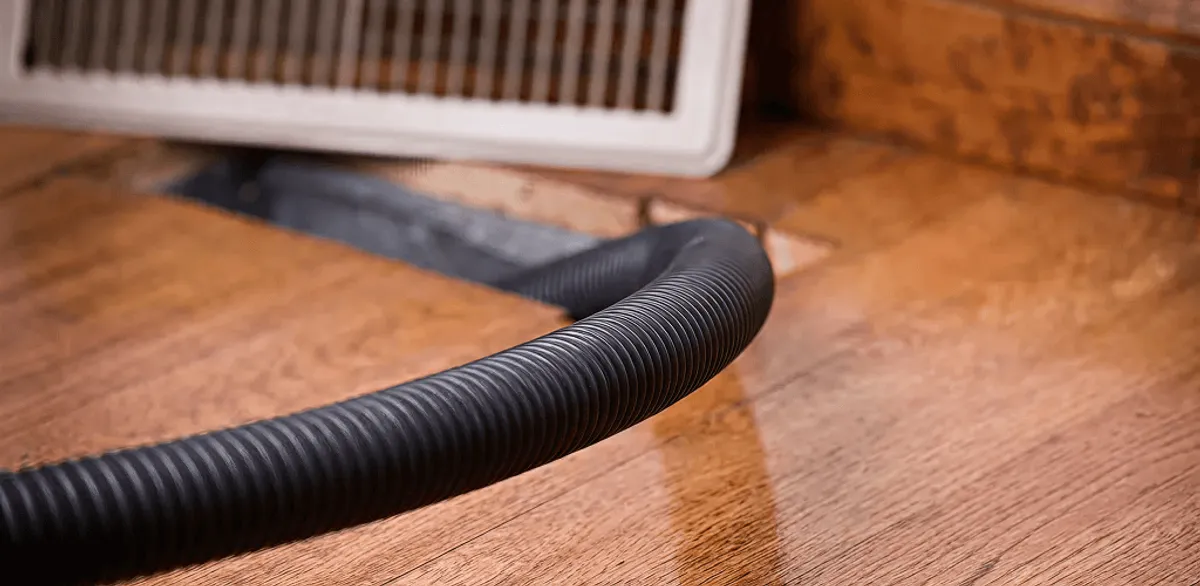 Air duct cleaning hose inserted into a floor vent for ductwork cleaning in Boston, MA