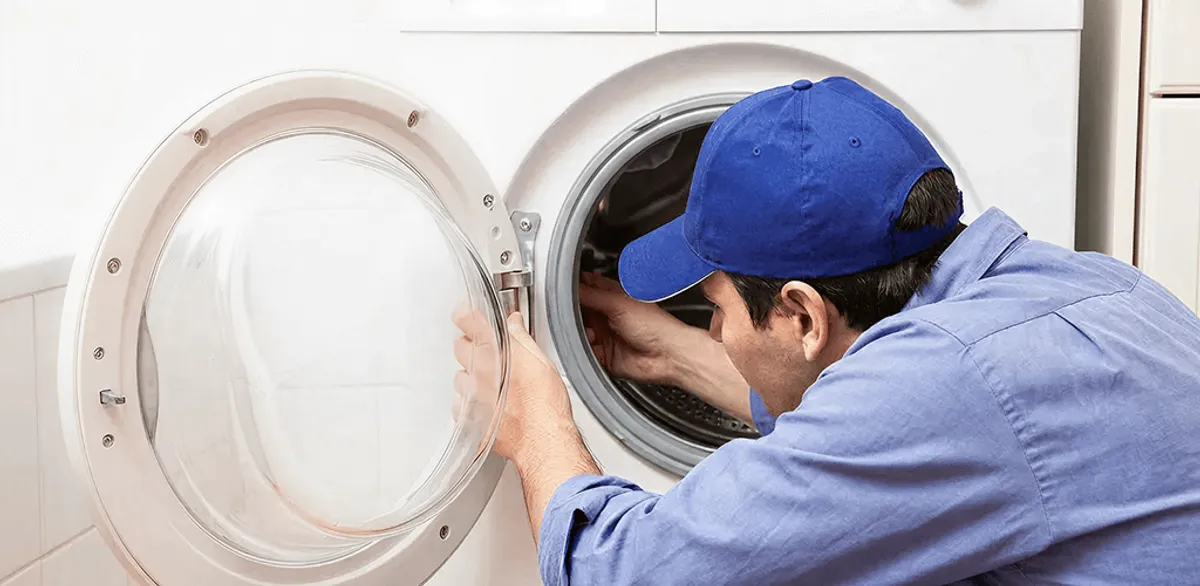Washing machine repair handyman inspecting a front-load washer drum in Boston, MA