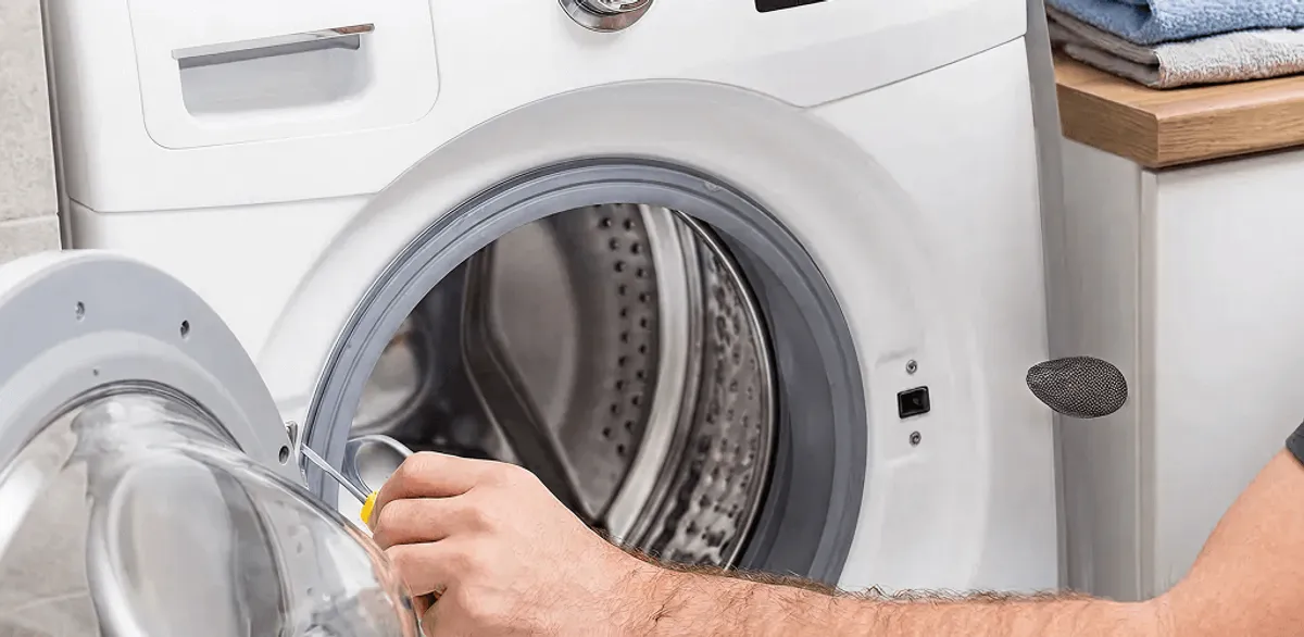 Handyman repairing a front-load washing machine and inspecting the drum in Boston, MA
